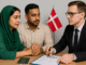 Pakistani couple consulting lawyer for Denmark spouse visa with passport and Danish flag in background